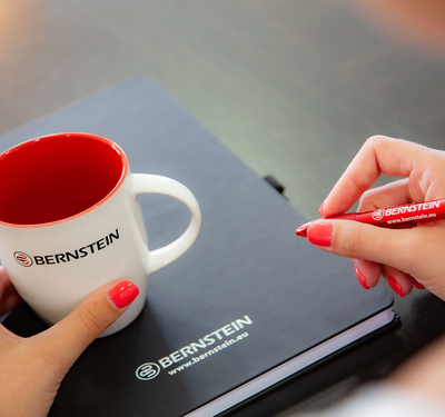 Eine Kaffeetasse mit BERNSTEIN Logo auf einem BERNSTEIN Notizbuch