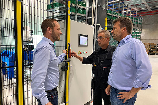 3 employees stand in front of a safety fence with a BERNSTEIN SLC switch